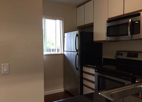 A kitchen with a black refrigerator and stainless steel appliances.