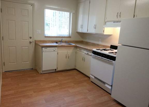 A kitchen with white appliances and wooden floors.