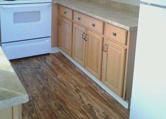 A kitchen with wooden cabinets and a white stove.