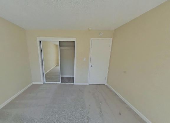 A room with a carpeted floor and two doors, one of which is open.