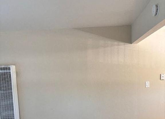 A room with a carpet floor and a wall-mounted air conditioner unit.