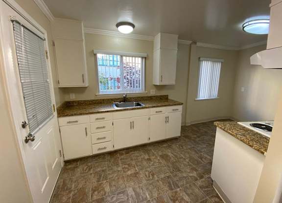 A kitchen with white cabinets and a brown countertop.