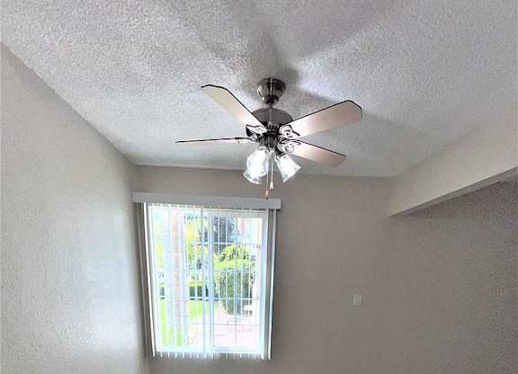 A room with a ceiling fan and a window letting in light.