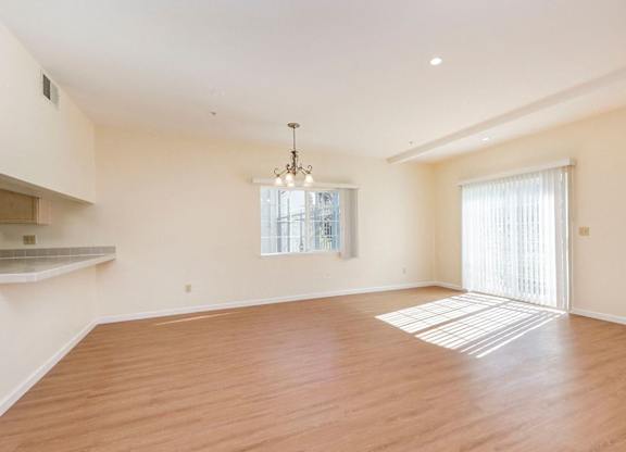 A large empty room with wooden floors and a chandelier.