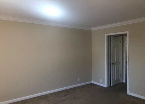 a empty living room with a door to a hallway