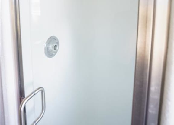 a white shower in a bathroom with a glass door