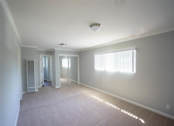 an empty living room with a door to a hallway and a window