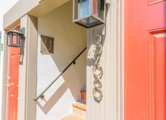 the front door of a house with stairs and a light