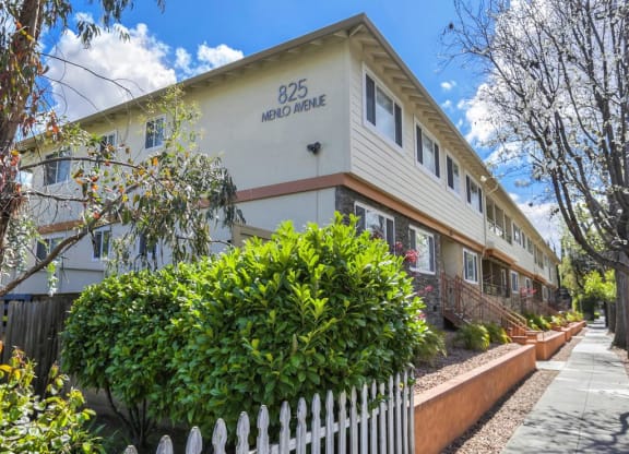 A white picket fence in front of a building with the number 825 on it.