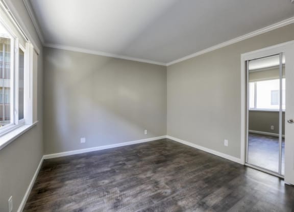A room with a wooden floor and a door leading to a hallway.