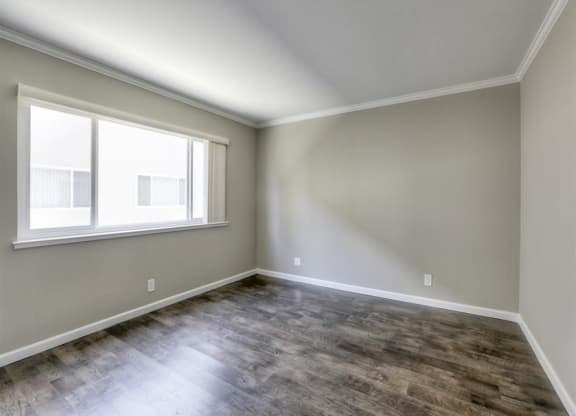 A room with a window and wooden flooring.