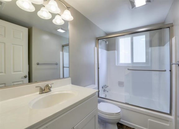 A white bathroom with a toilet, sink, and mirror.