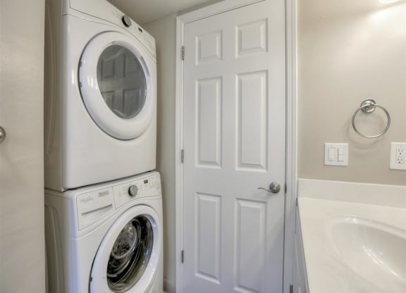 A white door is next to a stack of washers and dryers.
