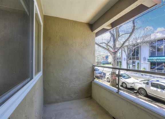 A balcony with a view of cars and trees.