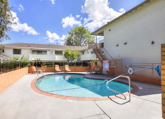 A small pool with a metal ladder and a small patio area with chairs.