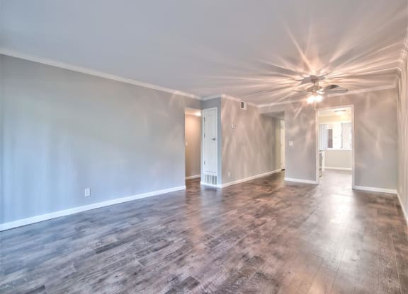 A room with a ceiling fan and wooden flooring.
