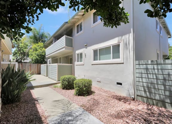 A modern two-story house with a grey exterior and a small garden in front.