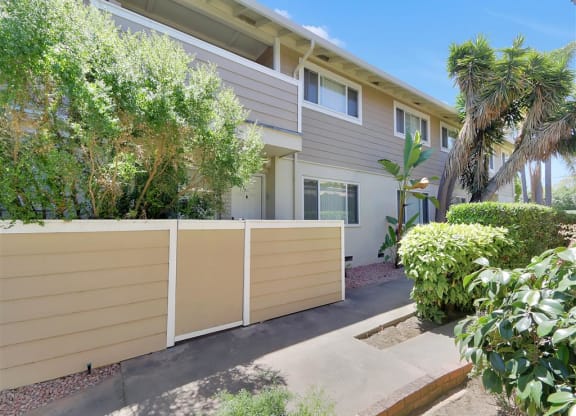 A modern two-story house with a beige fence and a small garden in front.