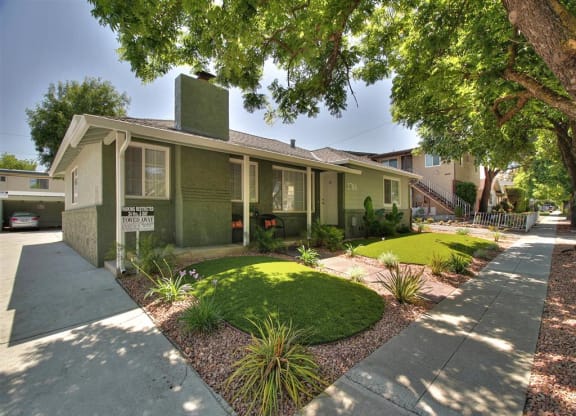 a small green house with a sidewalk and lawn