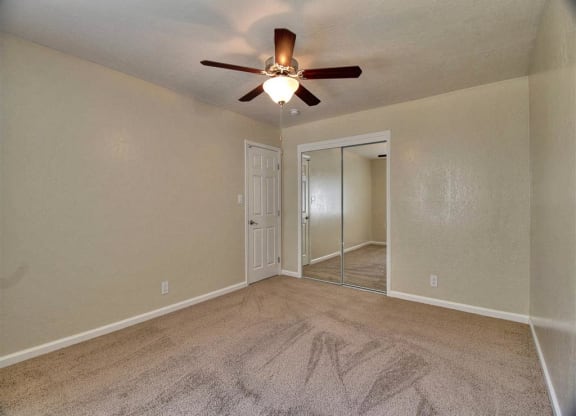 an empty living room with a ceiling fan and a mirror