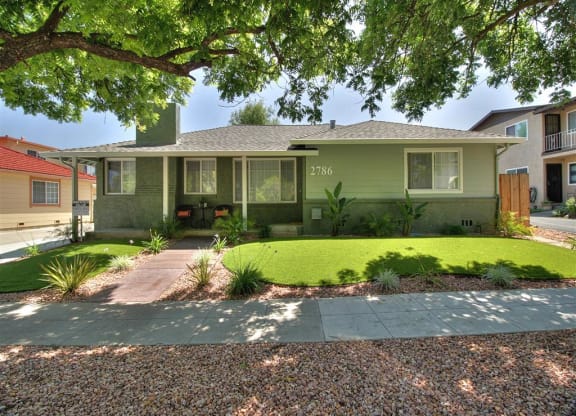 a green house with a yard and a sidewalk