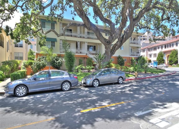 Two cars parked on the side of a street in front of apartment buildings.