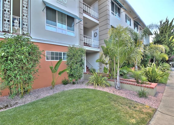 A building with a balcony and a green lawn in front.
