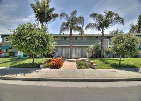 A building with a green lawn and trees in front.