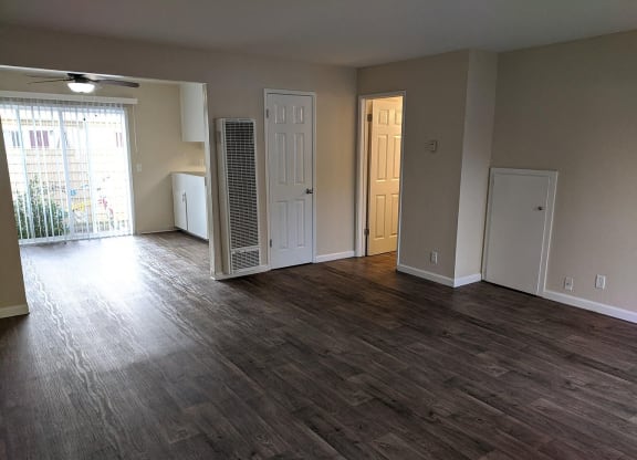 an empty living room with wood flooring and a closet