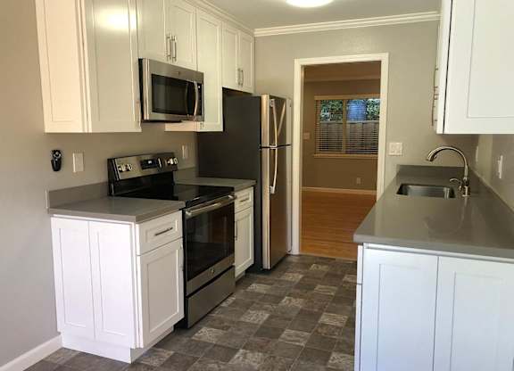 A kitchen with white cabinets and a black refrigerator.