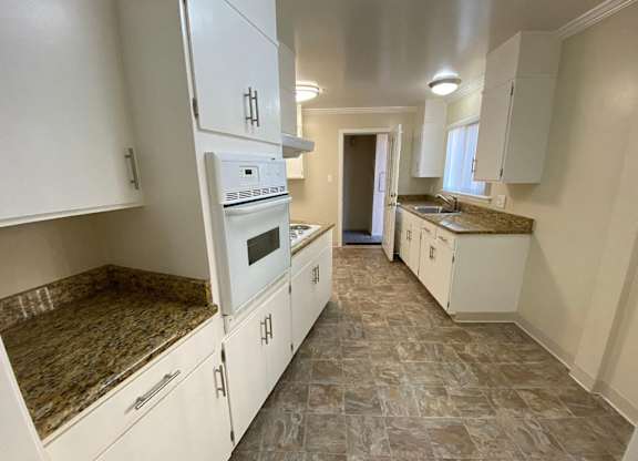 A kitchen with white cabinets and a granite countertop.
