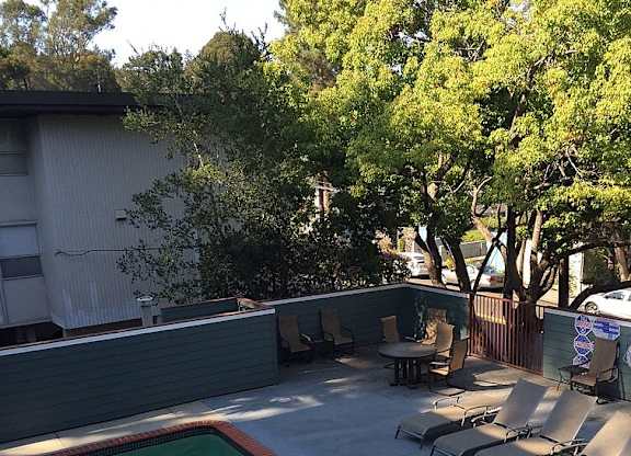 A pool surrounded by trees and chairs.