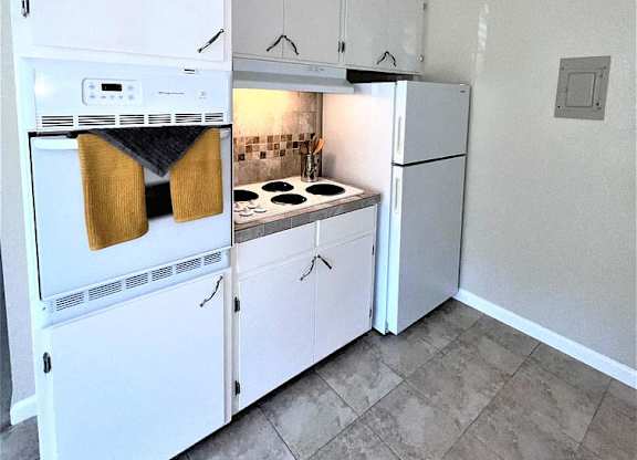 A kitchen with white cabinets and a white oven.