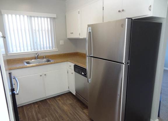 A kitchen with a stainless steel refrigerator and wooden floors.