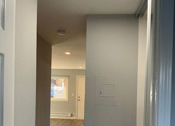 A hallway with a white door on the right and a white wall on the left.