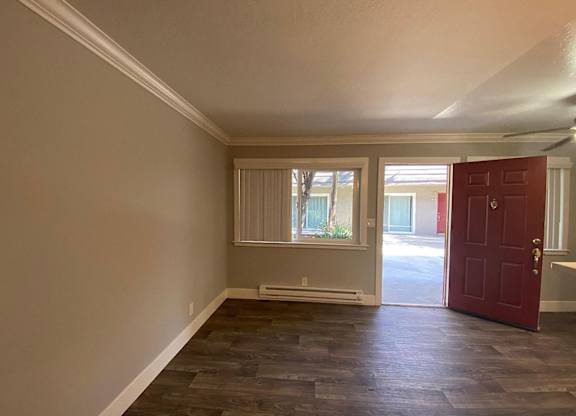 A room with a red door and a window with blinds.