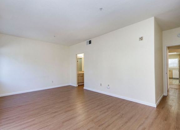 A large empty room with wooden floors and white walls.