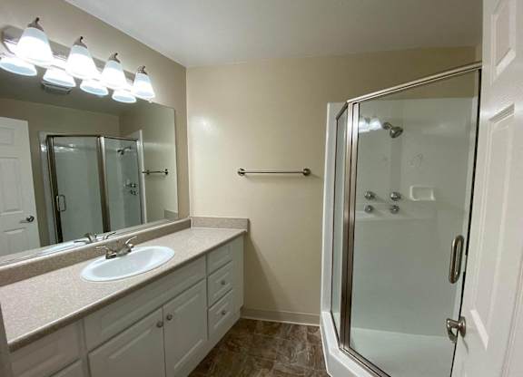 A bathroom with a sink, mirror, and shower.
