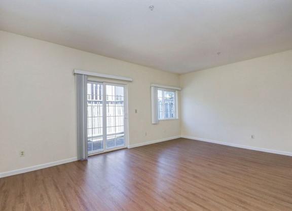 A room with wooden floors and two windows.