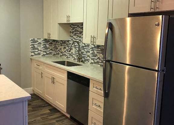 A kitchen with a stainless steel refrigerator and white cabinets.