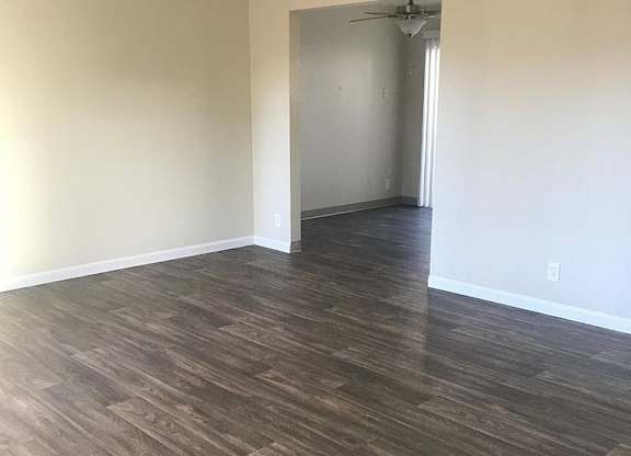 A room with wood flooring and a doorway leading to another room.