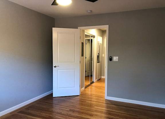 A room with a white door and wooden floor.