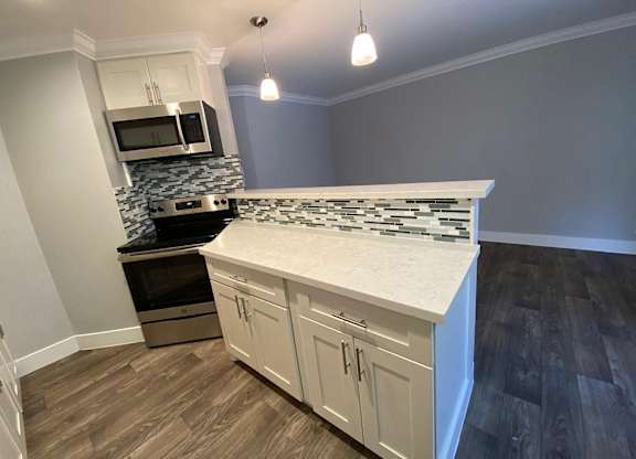 A kitchen with a white counter top and wooden cabinets.