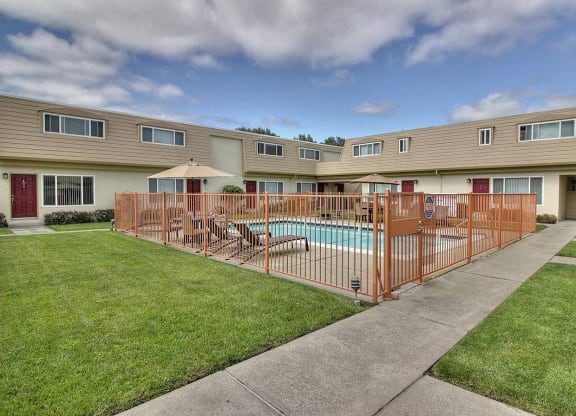a yard with a swimming pool behind a fence