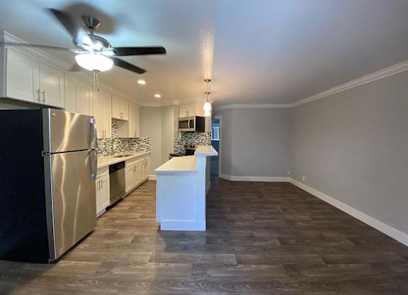 A kitchen with a refrigerator, sink, and countertop.