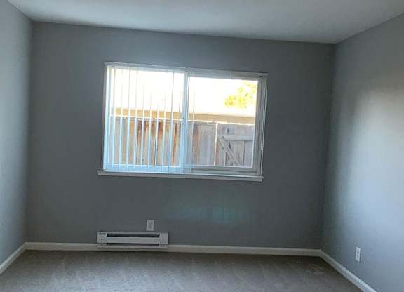 A room with a window and a radiator on the floor.