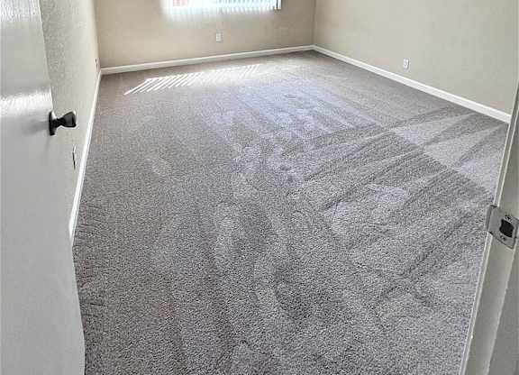 A room with a carpeted floor and a window.
