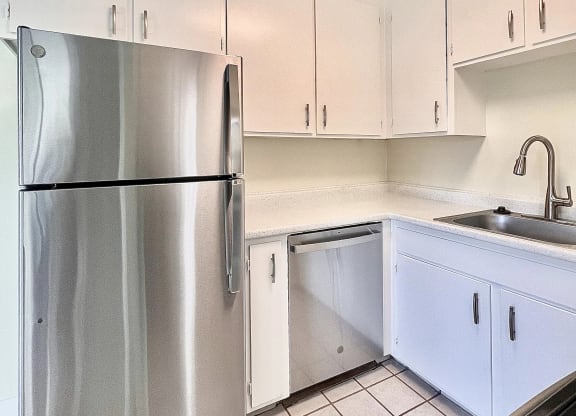 a kitchen with white cabinets and a stainless steel refrigerator