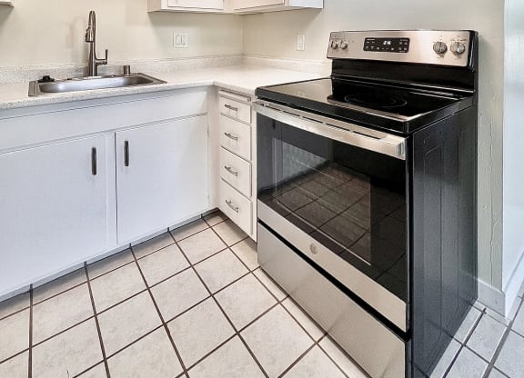 a kitchen with white cabinets and black appliances and a sink