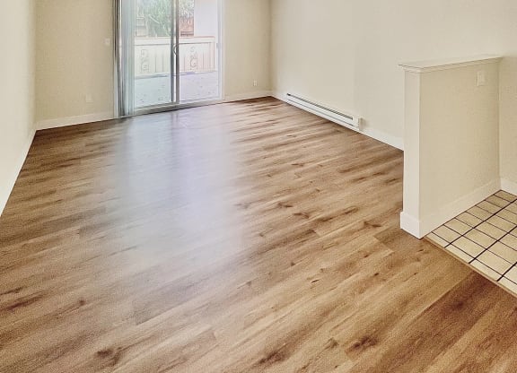 an empty living room with wood flooring and a sliding glass door